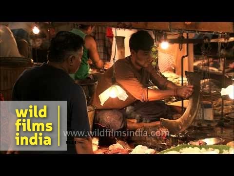 Man cut fishes below photographs of Hindu gods and goddesses in Kolkata